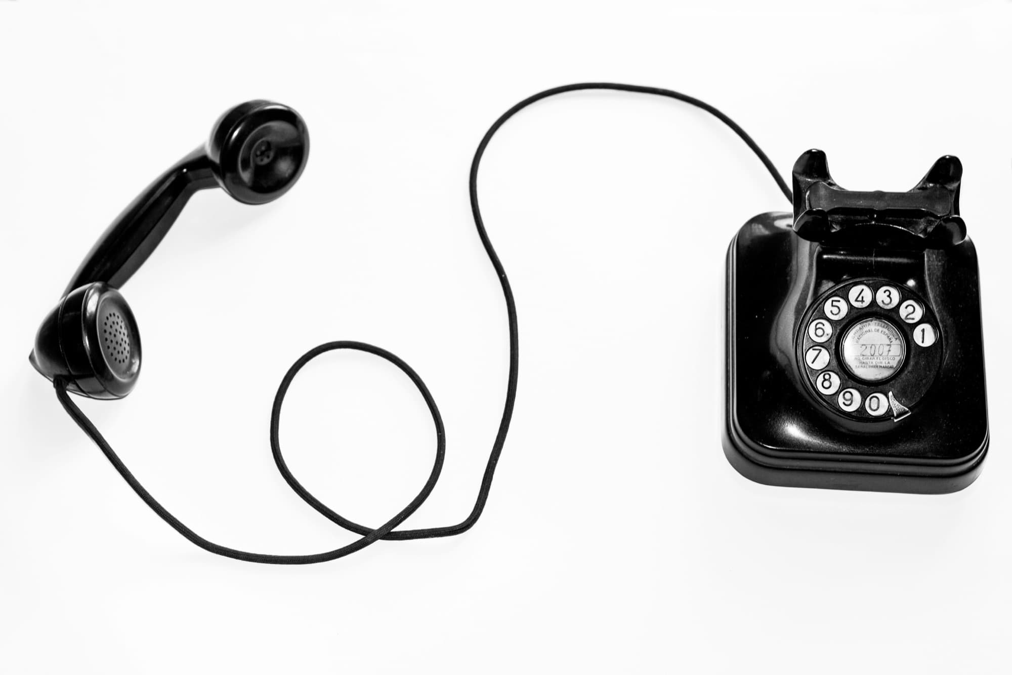 A vintage rotary telephone photographed from above, handset lifted off the cradle.